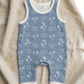 Miki Miette baby romper with blue and white palm tree pattern on a textured fabric background